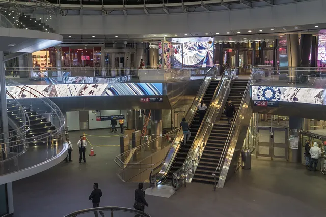 Video screens wrap the balconies of the Fulton Center transit hall above its escalators.